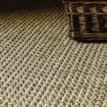 Detail shot highlighting the durable, chunky weave and color of a sisal carpet under low light.